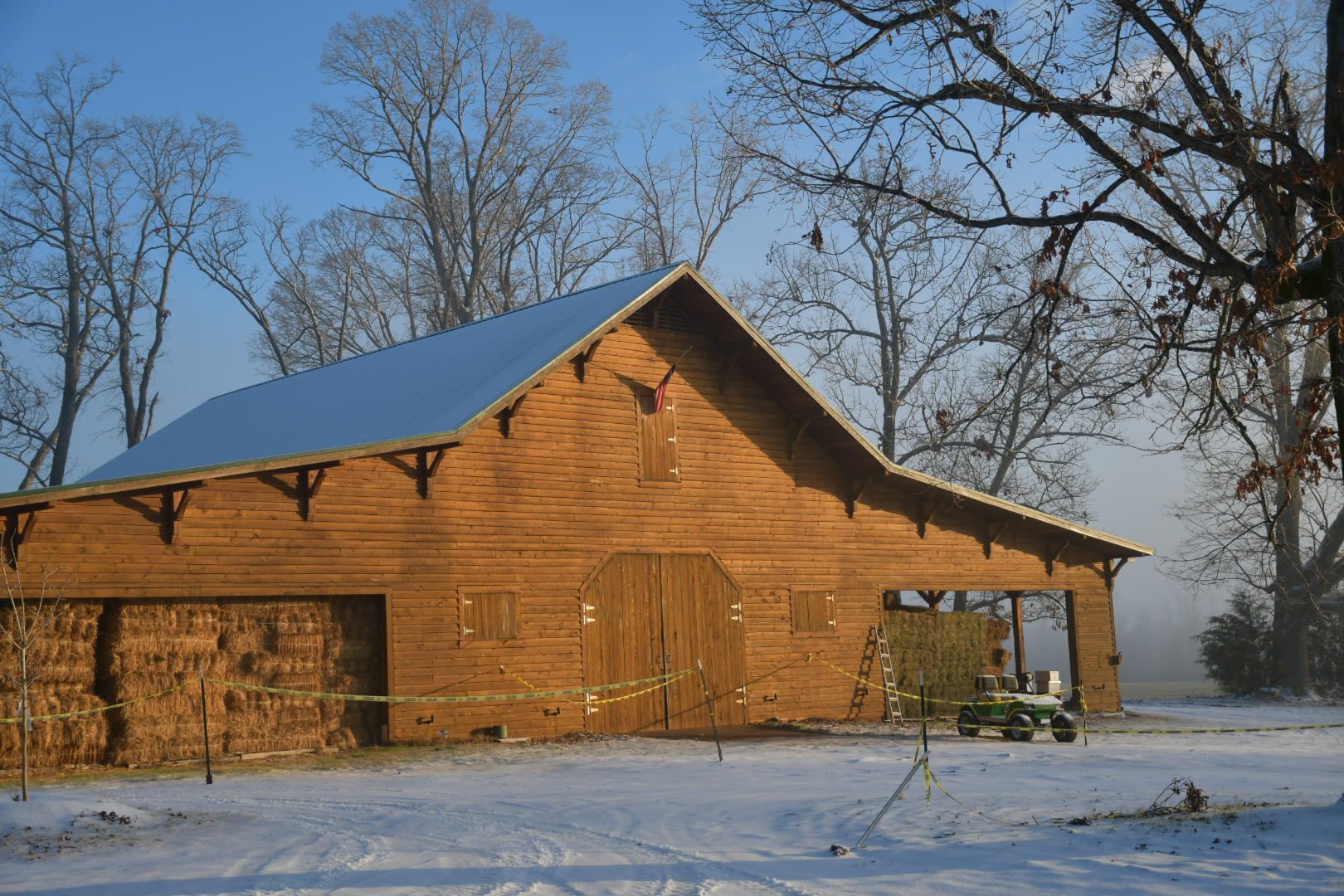 The wooden barn in winter snow with the American flag